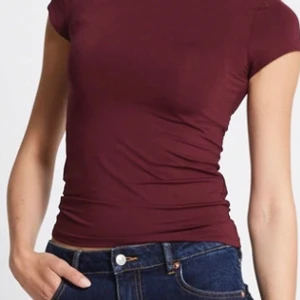 Vinröd kortärmad topp - Snygg vinröd topp med korta ärmar och en tight passform. Perfekt för en stilren look. Tillverkad i ett mjukt och bekvämt material.