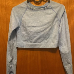 Ljusblå croppad tröja - Säljer en ljusblå croppad tröja med långa ärmar. Perfekt för en avslappnad stil. Tröjan har en enkel design med rund hals och är tillverkad i ett mjukt material.
