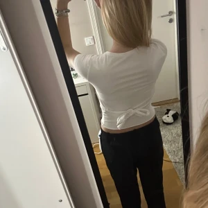 Vit croppad topp med knyt - Säljer en vit croppad topp med korta ärmar och knytning i ryggen. Perfekt för en stilren och avslappnad look. Passar bra till både jeans och kjol.