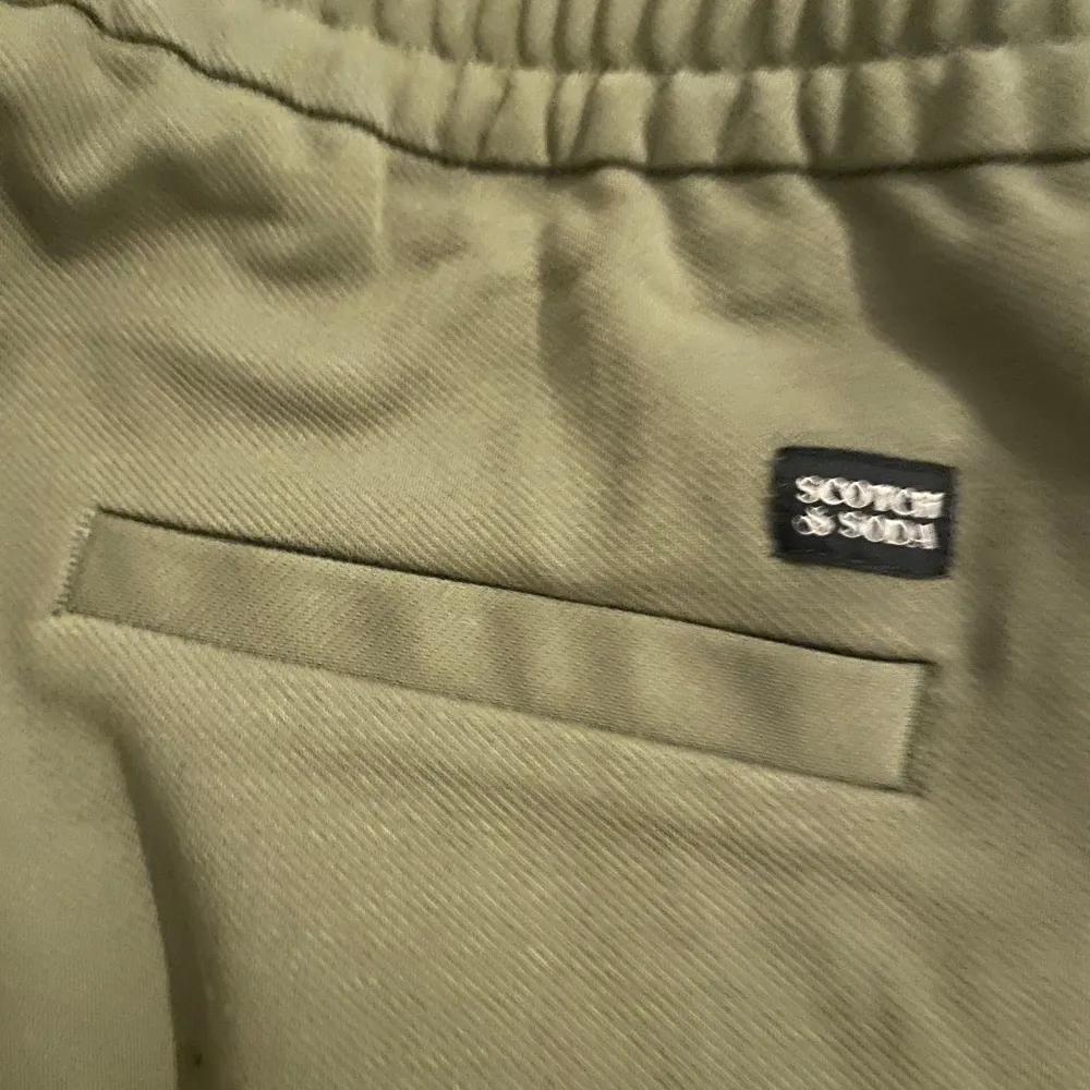 Snygga mjukis byxor från Scotch & Soda i en avslappnad slim fit. Byxorna har en elastisk midja med snörning för extra komfort. Perfekta för en stilren och bekväm look. Storlek 14 år (S) o använda. Farkut & Housut.