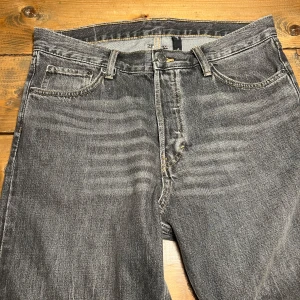 Grå Weekday jeans - Snygga grå jeans från Weekday i en klassisk straight fit. De har en midwaist och är tillverkade i bomull. Perfekta för en avslappnad stil med fem fickor och knappgylf. Finns ett litet märke på ena underbenet (se bild) där av det låga priset. 