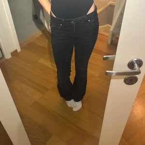 Svarta jeans från Zara - Snygga svarta lågmidjade jeans från Zara. De har en knapp och dragkedja framtill och är perfekta för en stilren look. Storlek 32 men väldigt stretchiga så passar nog en 34 eller 36 också. Lite trådar har gått upp på benet men absolut inget man tänker på🤗