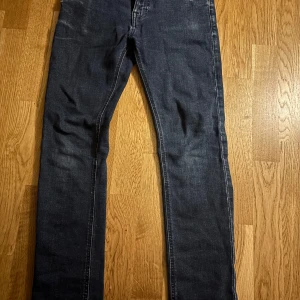 Mörkblå jeans från Nudie Jeans - Snygga grå/blå jeans från Nudie Jeans med en populär slim/skinny fit. Dom är i storlek 28/30 och i bra skick. Pris kan diskuteras vid snabb affär! Tveka inte på att höra av er :)
