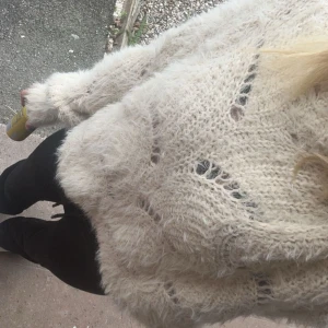 Beige stickad tröja - Mysig beige stickad tröja med ett unikt hålmönster. Perfekt för kyliga dagar med sin fluffiga textur och långa ärmar. En stilren och bekväm tröja som passar till många tillfällen.
