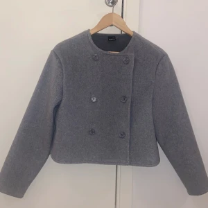 Grå kappa från Gina Tricot - nygg grå kappa från Gina Tricot i storlek XS.(passar även storlek S) Den har en stilren design med dubbelknäppning och långa ärmar. Perfekt för kyligare dagar och ger en elegant touch till din outfit. Den är helt ny utan prislapp, använd endast en gång!