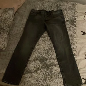 Svarta jeansbyxor - Ett par mörk gråa/svarta Jack and Jones jeans i storleken w32 L30 o modell slim/glenn.   Dem har bara används 2-3 ggr så är typ nya👍nypris 700 mitt pris 299