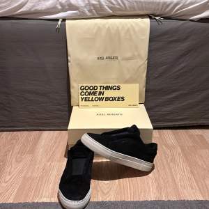 Snygga svarta sneakers från Axel Arigato med en stilren design. Skorna har en vit sula och är tillverkade i mocka. Perfekta för en avslappnad och trendig look.