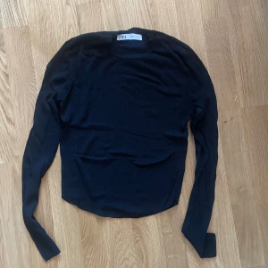 Svart ribbad tröja från Zara stl S - Säljer en stilren svart ribbad tröja från Zara. Tröjan har långa ärmar och en figurnära passform som passar perfekt till både jeans och kjol. Perfekt för en chic och enkel look.