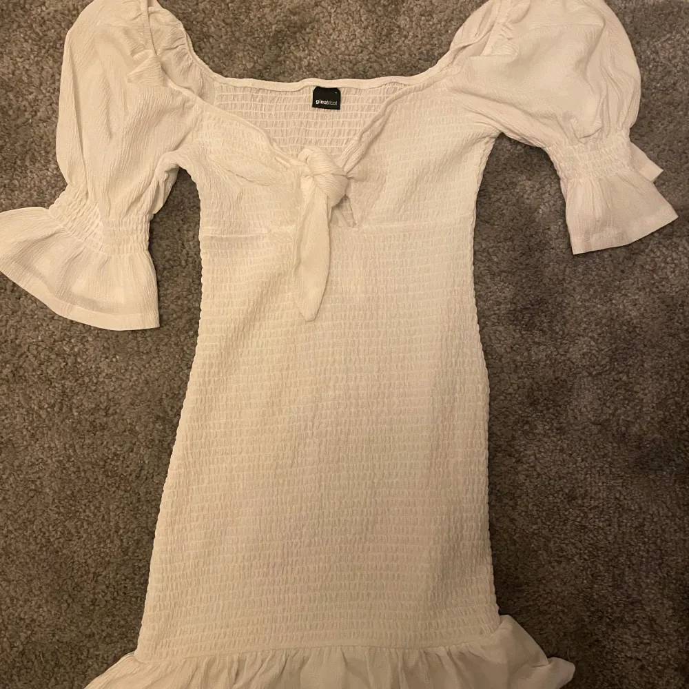 Säljer en söt vit klänning från Shein med knyt framtill och volangdetaljer vid fållen. Klänningen har korta puffärmar och en smickrande passform. Perfekt för sommarens alla tillfällen! 🌸. Mekot.