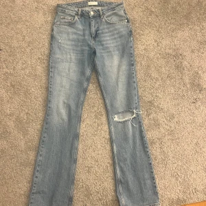Blå jeans med slitningar - Snygga blå bootcut jeans från Gina tricot med slitningar på ena benet. Inga defekter. Kommer ej till användning. Skriv för flera frågor privat💗