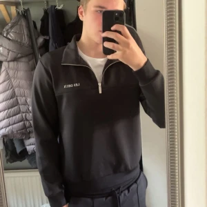 Svart tröja med dragkedja från Les Deux - Les Duex half zip i väldigt bra skick. Storlek M. Lite för kort för mig som är 1,88 lång