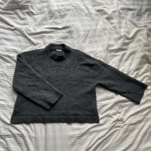 Grå stickad tröja från Gina Tricot - Säljer en mysig grå stickad tröja från Gina Tricot i premiumkvalitet. Tröjan har en klassisk design med långa ärmar och ribbade kanter vid ärmslut och nederkant. Perfekt för kyliga dagar!