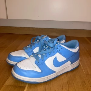 Nike Dunk i blått och vitt - Snygga Nike Dunk sneakers i en fräsch kombination av blått och vitt. Skorna har en klassisk design med snörning och den ikoniska Nike-loggan på sidan. Perfekta för en sportig och trendig look.💕