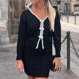 Rosett tröja - Säljer denna ursnygga tröja med vita detaljer och rosetter som aldrig kommit till användning. Perfekt för en stilren look. Koftan har en v-ringad design och långa ärmar!