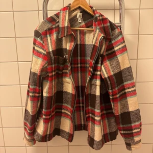 Rutig overshirt från River Island - Säljer en snygg rutig overshirt från River Island i storlek L. Jackan har en klassisk krage och dragkedja framtill. Färgerna är en mix av rött, brunt, beige och lite turkos. Snyggt med lager-på-lager. Säljer då den inte längre passar. Ursprungligen köpt för 599 kr.