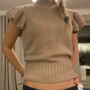 Beige/lila stickad topp med volangärmar - Säljer en snygg beige stickad topp med volangärmar. Den har en ribbad kant vid midjan och halsen, vilket ger en fin passform. Lila beige aktiv färg🩷