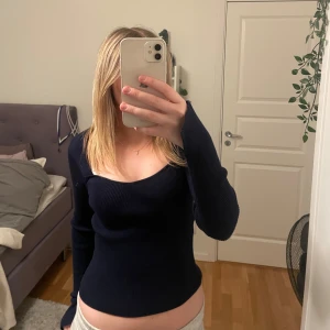 Mörkblå ribbad topp från Gina - Säljer en stilren mörkblå ribbad topp från Gina. Toppen har en fyrkantig urringning och långa ärmar med en slit på slutet av ärmarna.