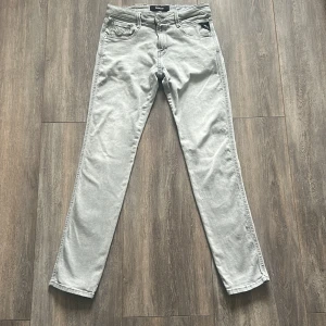 Grå jeans från Replay - Snygga grå jeans från Replay i modellen Anbass. De har en klassisk femficksdesign och en bekväm passform. Perfekta för en stilren look.