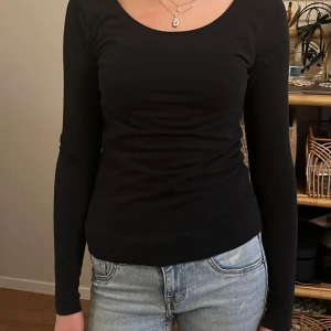 Svart långärmad topp - Snygg och enkel svart långärmad topp med rund halsringning. Perfekt för en stilren look och lätt att matcha med olika outfits. Passar bra till både jeans och kjol.