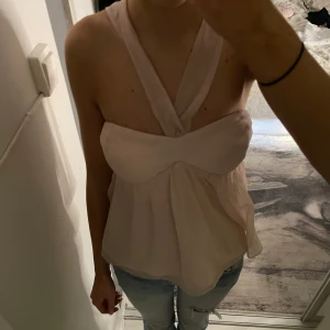 Rosa halterneck topp från Nelly - Säljer en söt rosa halterneck topp från Nelly. Toppen har en elegant drapering framtill och är perfekt för varma dagar. Den är tillverkad i ett lätt och luftigt material som ger en skön känsla.