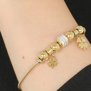 Guldarmband med fyrklöverberlocker  - Elegant guldarmband med glänsande pärlor och två fyrklöverberlocker. Armbandet har även en glittrig detalj i mitten som ger extra bling. Perfekt för attew lägga till en touch av lycka och stil till din outfit.14k  Guldpläterad.