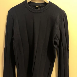 Mörkblå tröja från H&M - Säljer en stilren mörkblå tröja från H&M i slim fit. Tröjan har långa ärmar och en ribbad krage. Perfekt för en minimalistisk look.