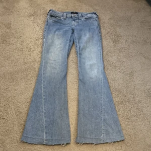 Blå jeans från True Religion 💕 - Snygga blå jeans från True Religion, lågmidjade och utsvängda ben. Ytterbenslängd 98 cm, innerbenslängd 78 cm, midjemått 70 cm. 💕