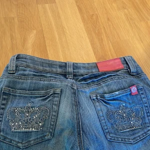 Victoria Beckham jeans - Snygga blå bootcut jeans från Monday med broderade kronor på bakfickorna. Jeansen har en låg midja och klassisk femficksdesign. Perfekta för en avslappnad stil med en touch av bling.