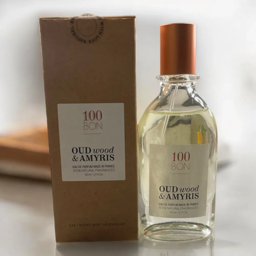 Upptäck den naturliga doften av Oud Wood & Amyris från 100 Bon. Denna Eau de Parfum är tillverkad i Frankrike med 100% naturliga ingredienser. Flaskan rymmer 50 ml och har en elegant design med en kopparfärgad kork. Perfekt för dig som älskar varma dofter.. Perfume.