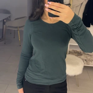 Mörkgrön långärmad topp  - Säljer en stilren mörkgrön långärmad topp från new yorker. den är i storlek M men är ändå generös. säljer denna pga att den aldrig kommer till användning