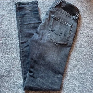 Grå replay jeans med slitningar - Snygga grå jeans från replay med coola slitningar på framsidan. De har en klassisk femficksdesign och en bekväm passform. Perfekta för en avslappnad stil. Storleken är 29/34