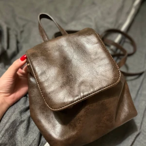 Brun ryggsäck från Brandy Melville  - “Säljer en mörkbrun Brandy Melville ryggsäck. I mycket gott skick!” “Finns inte längre att köpa.”