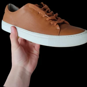 Bruna sneakers från Sneaky Steve - Snygga bruna sneakers i skinn från Sneaky Steve med vit sula och matchande bruna snören. Perfekta för en stilren look.