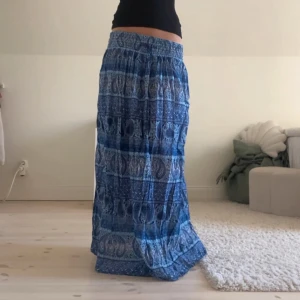Blå långkjol med paisleymönster - Säljer en vacker blå långkjol med ett detaljerat paisleymönster. Kjolen har en elastisk midja med knytband. Storlek 34, men strchig så passar xs-m😊