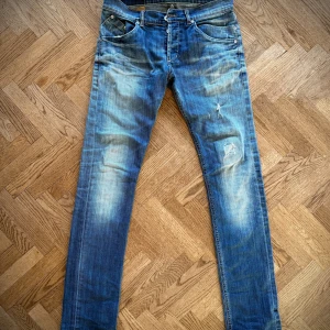 Blå jeans från Dondup stl 30 - Snygga blå jeans från Dondup med en klassisk femficksdesign och slitna detaljer. Jeansen har en knappgylf och är tillverkade i ett robust denimtyg. Perfekta för en avslappnad stil. Köpte jeansen på Plick men de var tyvärr för små (jag har stl 31)! Sista bilden är lånad av förra annonsen. 