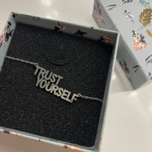 Halsband IOAKU - Snyggt silverfärgat halsband med texten 'TRUST YOURSELF' från IOAKU. Perfekt för att ge en fin touch till din stil. Äkta silver!! Pris kan diskuteras 