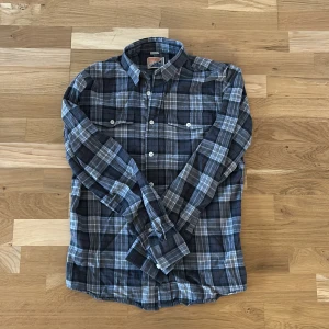 Rutig skjorta  - Snygg rutig skjorta i gråa toner. Skjortan har långa ärmar och klassisk krage med knappar framtill. Skjortan är i storlek S och är i gott skick!