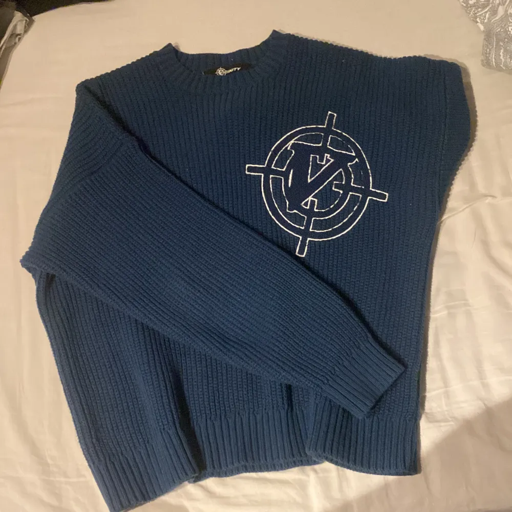 Säljer en snygg blå stickad tröja från Vicinity med ett stort vitt emblem på framsidan. Tröjan har långa ärmar och ribbade kanter som ger en skön passform 10/10 kvalite . Neuletakit & Villapaidat.