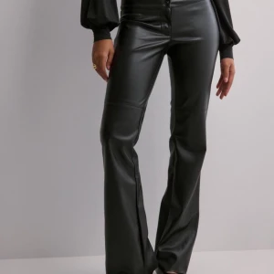 Svarta skinnbyxor - Snygga svarta skinnbyxor från Nelly, slutsålda på hemsidan. Har låg midja och är bootcut. Endast använda en gång så är som nya, nypris var 500kr 