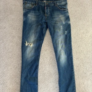 Blå jeans från Dsquared2 - Säljer ett par snygga blå jeans från Dsquared2 med slitna detaljer och en klassisk femficksdesign. Jeansen har en normal/slim passform. Kontakta mig för mer info Svante//