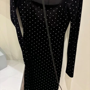 Svart prickig klänning från H&M - Snygg svart klänning från H&M i storlek XS. Den har ett prickigt mönster och är långärmad, perfekt för festliga tillfällen. Klänningen är tight och har en elegant stil som passar både till vardags och fest.