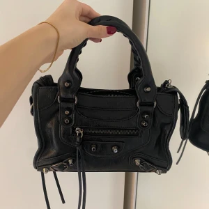 Balenciaga liknande väska - Skit snygg skinn väska som liknar city bagen från Balenciaga. Använd några gånger men i väldigt bra skick! 💞 Väskan har tre innerfack samt ett yttre fack, dessutom medföljer ett band till väskan! 🤗