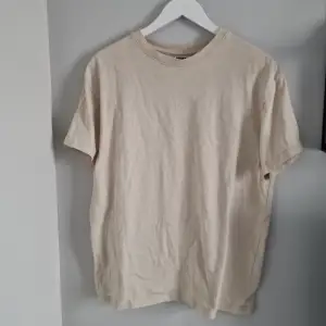 Säljer en stilren beige t-shirt från Urban Classics i storlek S. Den är i bra skick och perfekt för skate stil då där en loose fit och tjockare tyg. T-shirten är kortärmad och gjord av mjuk bomull, vilket gör den bekväm att bära hela dagen. 