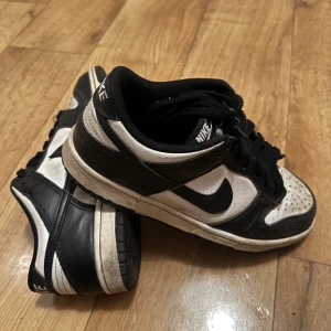 Nike Dunk i svart och vitt - Säljer ett par Nike Dunk i svart och vitt. Skorna har en klassisk design med snörning och är i bra skick. Lite smutsiga på bilen men går att rengöra! 