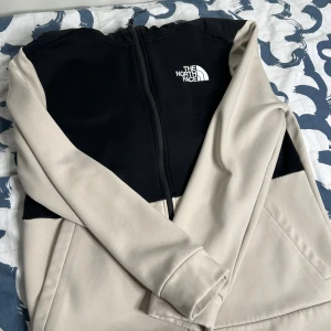 The North Face Hoodie - Säljer en snygg och bekväm jacka från The North Face i beige och svart för att jag bytte stil. Hoodie är perfekt för höst och vår. Den är i mycket bra skick. Jätte varmt och knappt använd. Skriv för mer info!