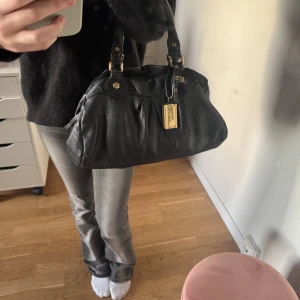 Marc Jacob’s väska - Säljer min supersnygga väska från Marc Jacobs då den inte kommer till användning längre. Enda defekten är en kaffe fläck inuti väskan annars är den som ny. Dust bag med kommer. Längd 39 cm och höjd ca 21 cm!