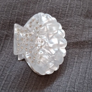 Vit hårklämma med pärldetaljer - Snygg och elegant vit hårklämma i form av en snäcka, dekorerad med små pärlor. Perfekt för att ge en extra touch till din frisyr, oavsett om det är till vardags eller fest. Klämman är robust och håller håret på plats hela dagen.