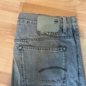 Grå jeans från G-Star RAW - Säljer ett par snygga grå jeans från G-Star RAW i storlek 34/34. De är i bra skick och har en klassisk straight passform. 