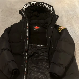 Svart jacka Zavetti Canada - Snygg svart jacka från Zavetti Canada med broderad logga på ärmen och insidan. Jackan har en hög krage och dragkedja framtill. Perfekt för kalla dagar med sin varma vaddering och stilrena design. Köpt för 1800kr. Helt ny lägsta kan gå 1400 Passar UNGDOMAR 13-17 beror på hur lång man är . Hör av er om ni undrar nåt