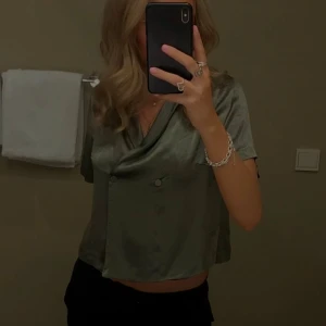 Olivgrön satinblus - Så fin olivgrön blus i satin med korta ärmar och omlottdetalj framtill. Från märket Stockholm 